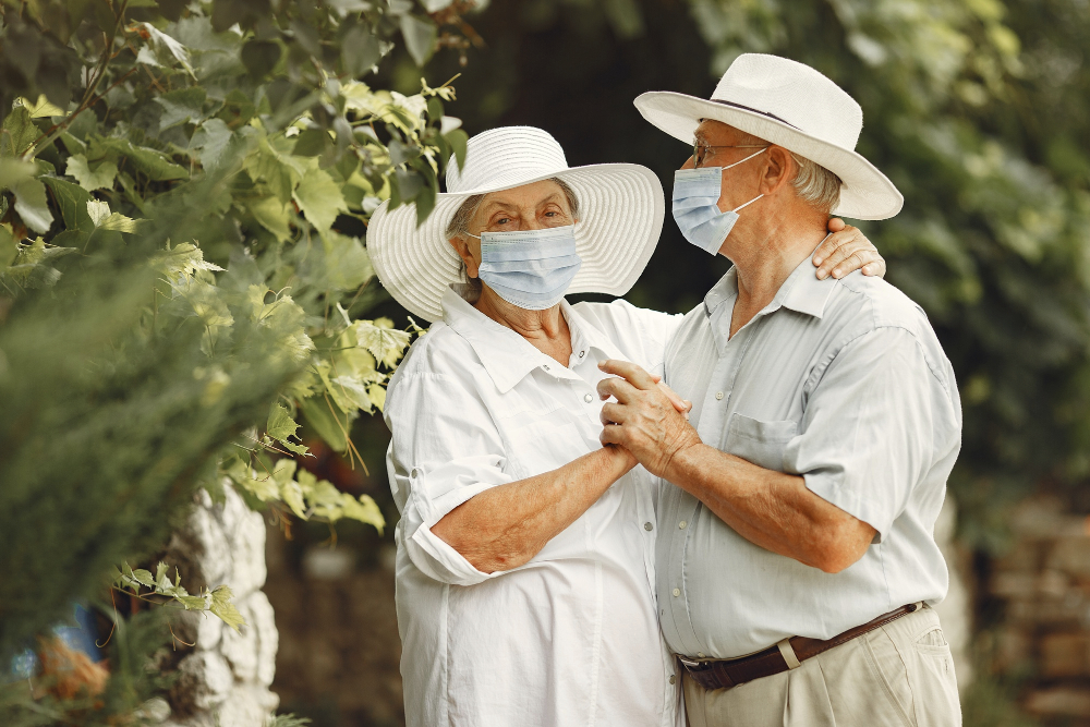 adult-couple-in-a-summer-garden-coromavirus-theme-people-in-a-medical-mask-handsome-senior-in-a-white-shirt.jpg