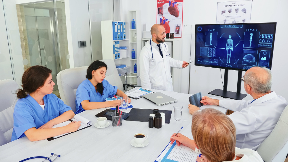 mature-medical-physician-explaining-treatment-to-nurses-during-healthcare-seminar-pointing-at-digital-monitor-clinic-herapist-discussing-with-colleagues-about-disease-medicine-professional.jpg
